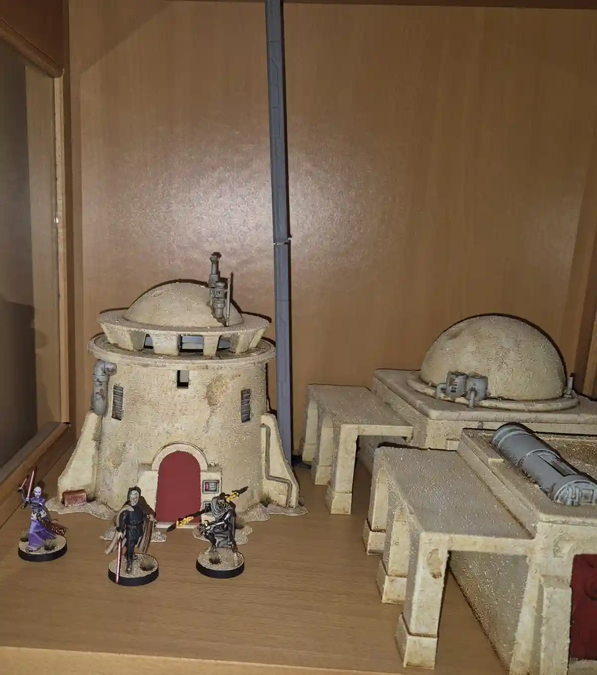 A diorama of a Star Wars-style Jedi Temple with miniature buildings and three painted action figures resembling Jedi or Sith…
