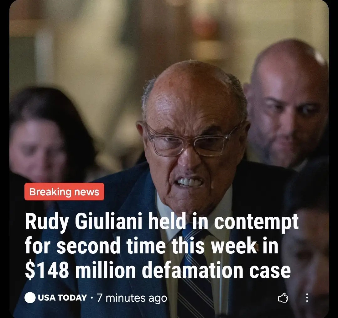A close-up photo shows Rudy Giuliani with a furious, teeth-baring expression, wearing glasses and a suit. Overlaid text…