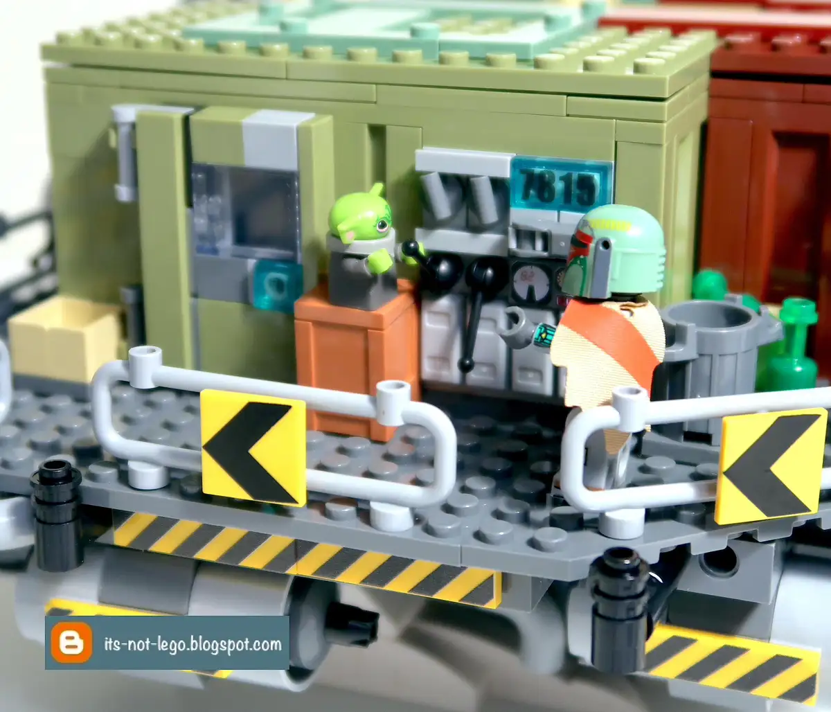 A close-up of a LEGO Star Wars diorama featuring a green-skinned Grogu minifigure standing on an orange block near a control…