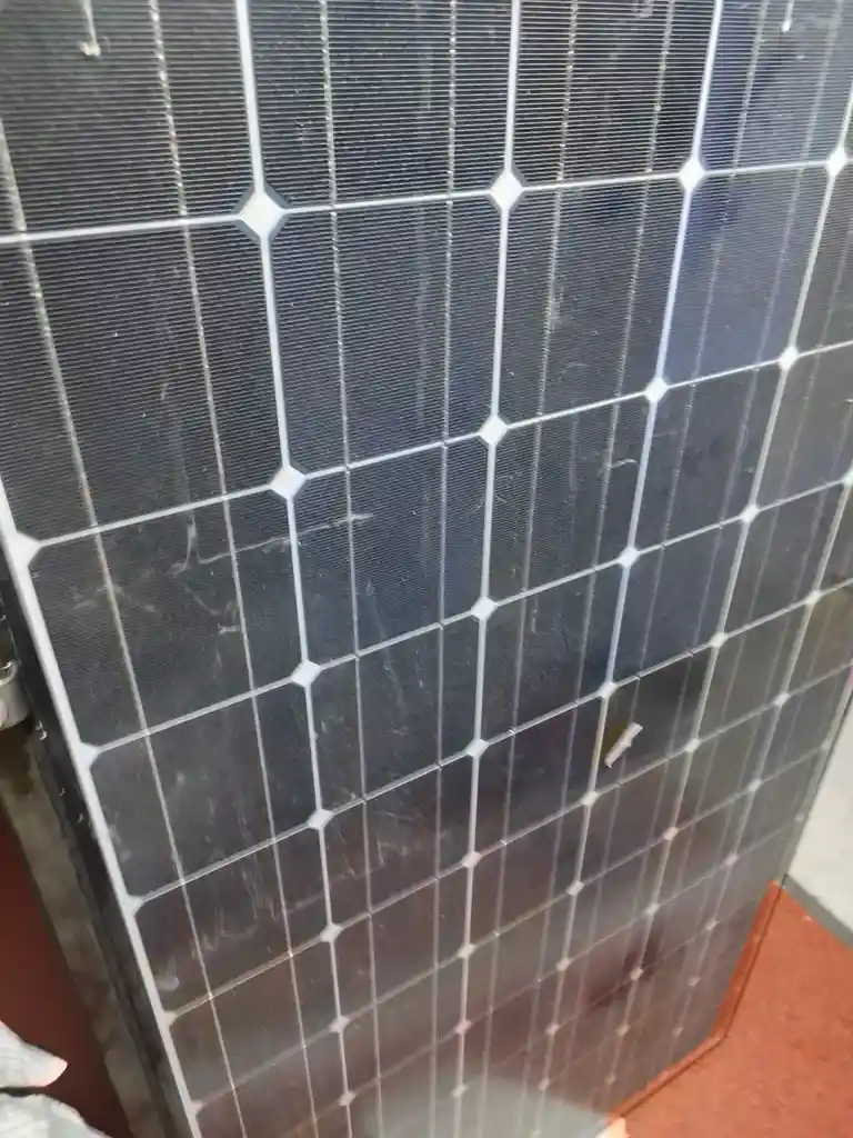A close-up of a dark blue solar panel that has been installed as a door, showing its grid of photovoltaic cells and white…