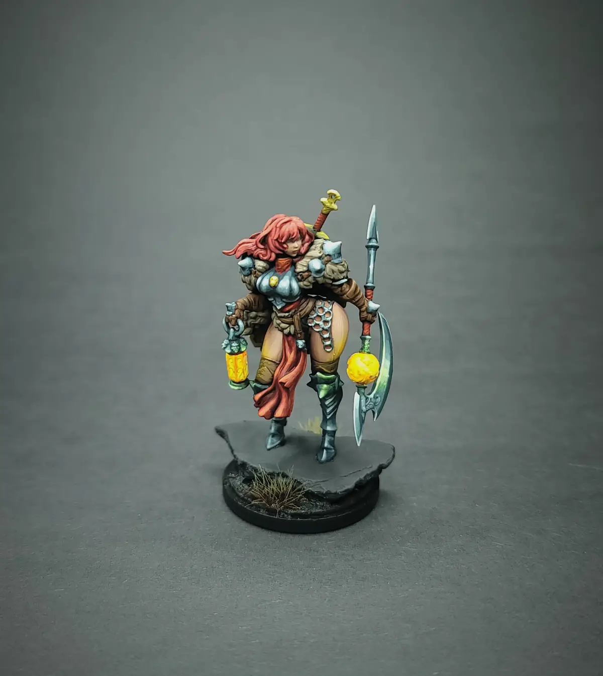A painted fantasy miniature of a female warrior with red hair, wearing armor and carrying a spear, a lantern, and a sword…