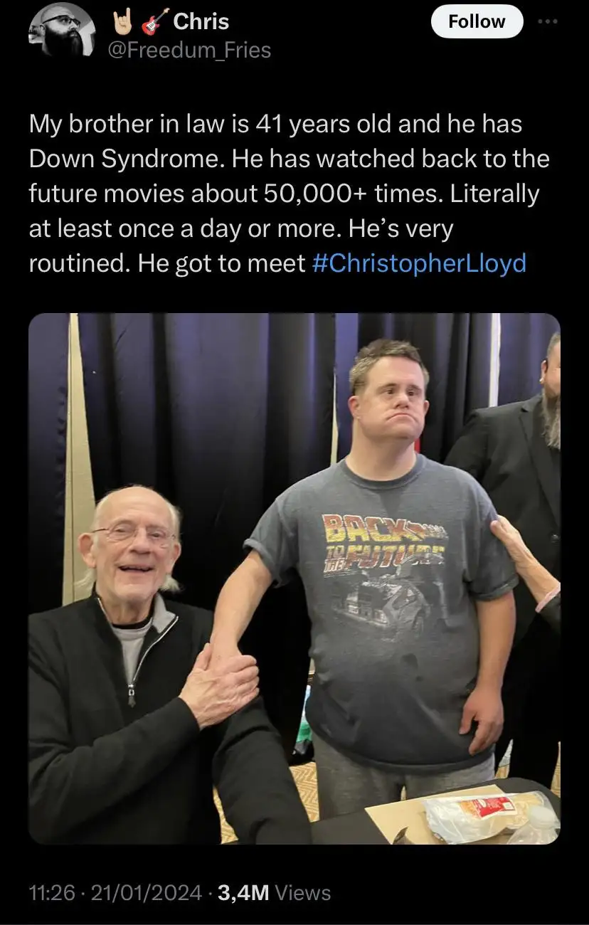 A man with Down Syndrome wearing a 'Back to the Future' t-shirt stands beside actor Christopher Lloyd, who is smiling and…