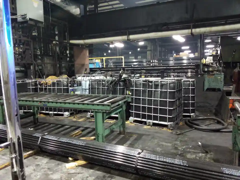 An industrial factory floor with metal pipes, conveyor rollers, and large black plastic totes. The overlaid text reads 'i'm…