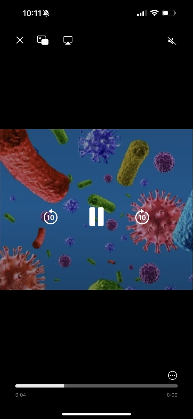 A phone screen shows a video player paused over a microscopic image of colorful bacteria and viruses. The video controls…