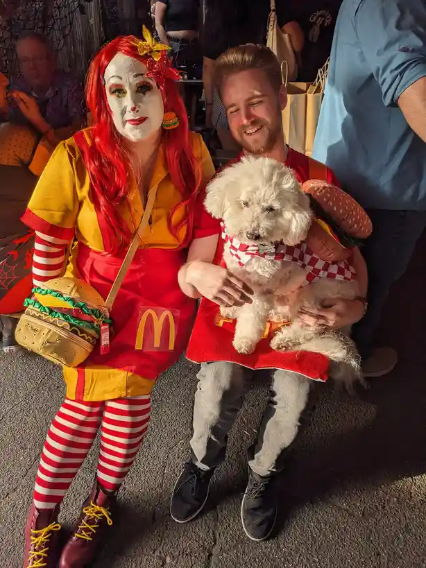 A person dressed as Ronald McDonald's female counterpart, with white face paint, red wig, and McDonald's branded outfit…