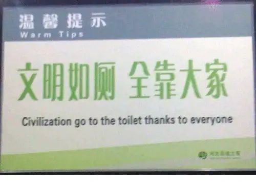 A public restroom sign in Chinese with green text on a white background, featuring the phrase '文明如厕 全靠大家' and its English…