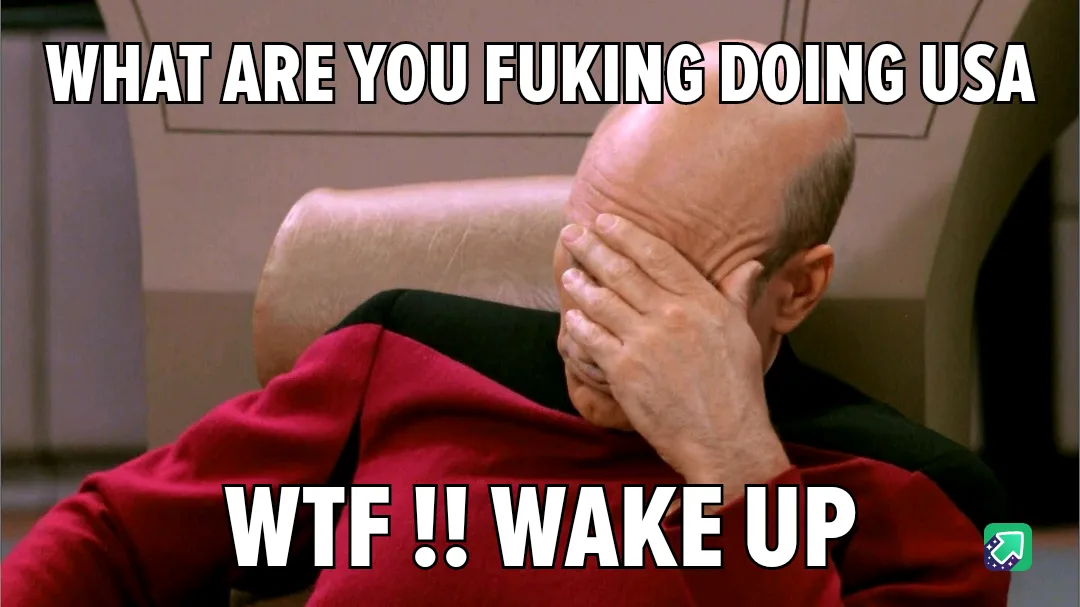 A bald man in a red Starfleet uniform sits in a chair, covering his face with his hand in a classic 'facepalm' gesture. The…