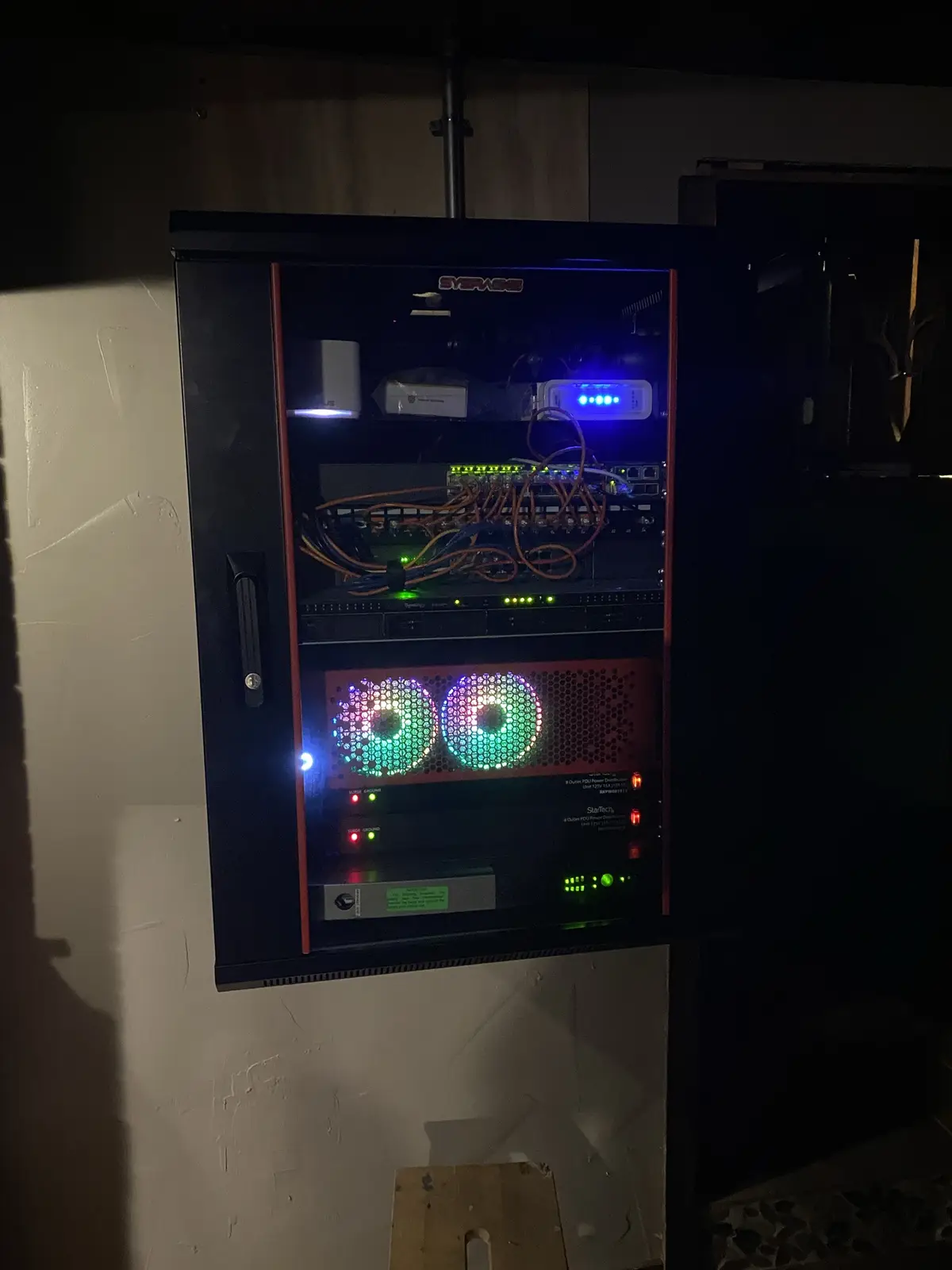 A black server rack with its door open, revealing internal hardware including a network switch, power distribution units…