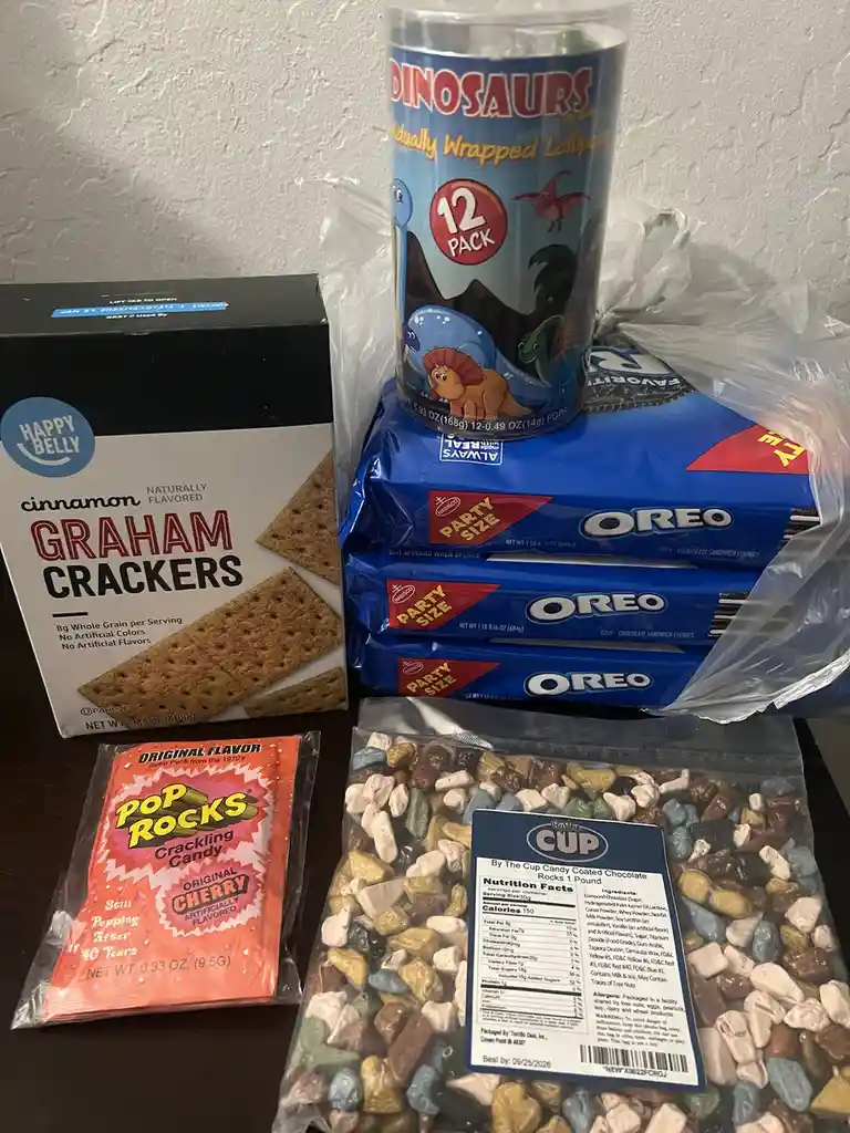 A collection of snack items including a box of cinnamon graham crackers, three large packages of Oreo cookies, a can of…