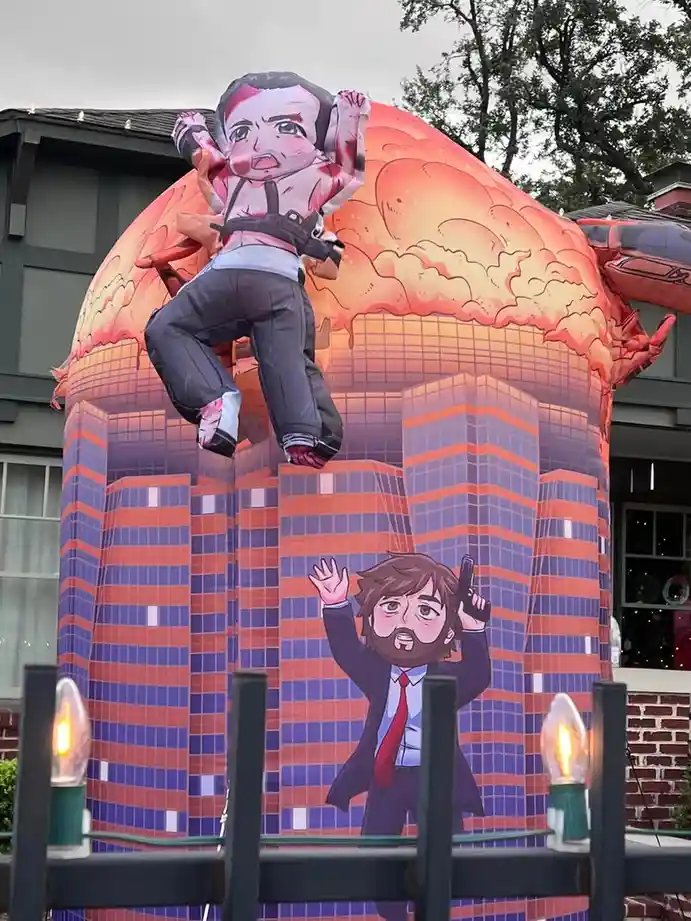 An inflatable Halloween decoration depicts a cartoon man in a suit being crushed by a giant crab, with another cartoon man…