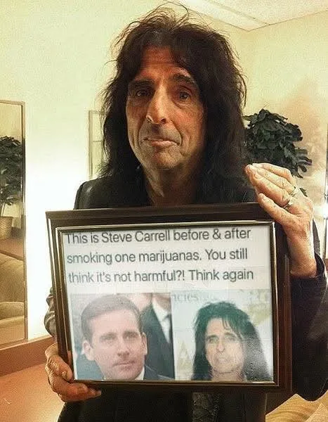 A man with long dark hair and a somber expression holds a framed photo showing a side-by-side comparison of Steve Carell's…
