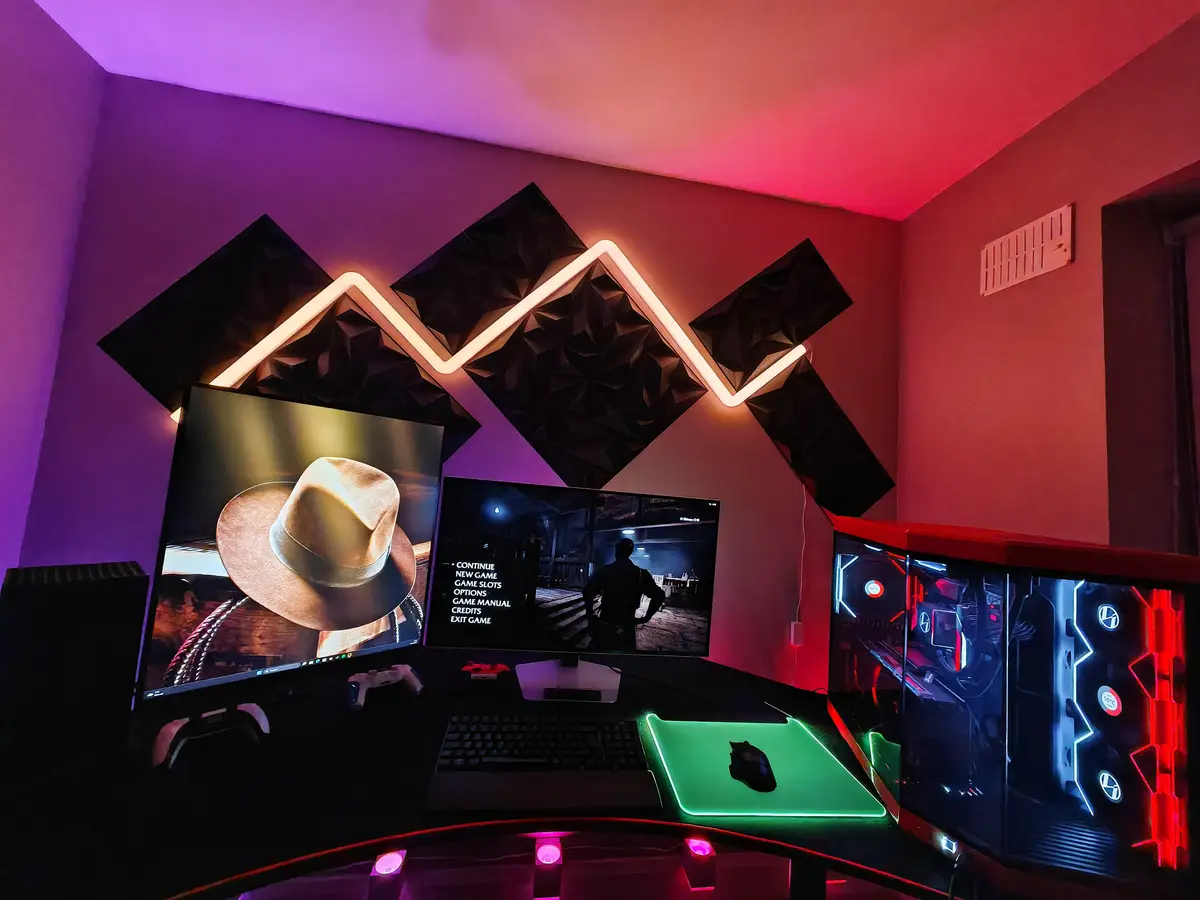 A high-end gaming setup with three monitors, a glowing green mousepad, and a custom PC with RGB lighting. The central…