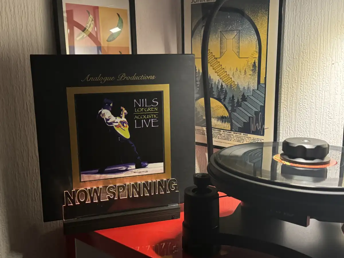 A framed vinyl record sleeve for 'Nils Lofgren Acoustic Live' by Analogue Productions sits on a red shelf next to a…