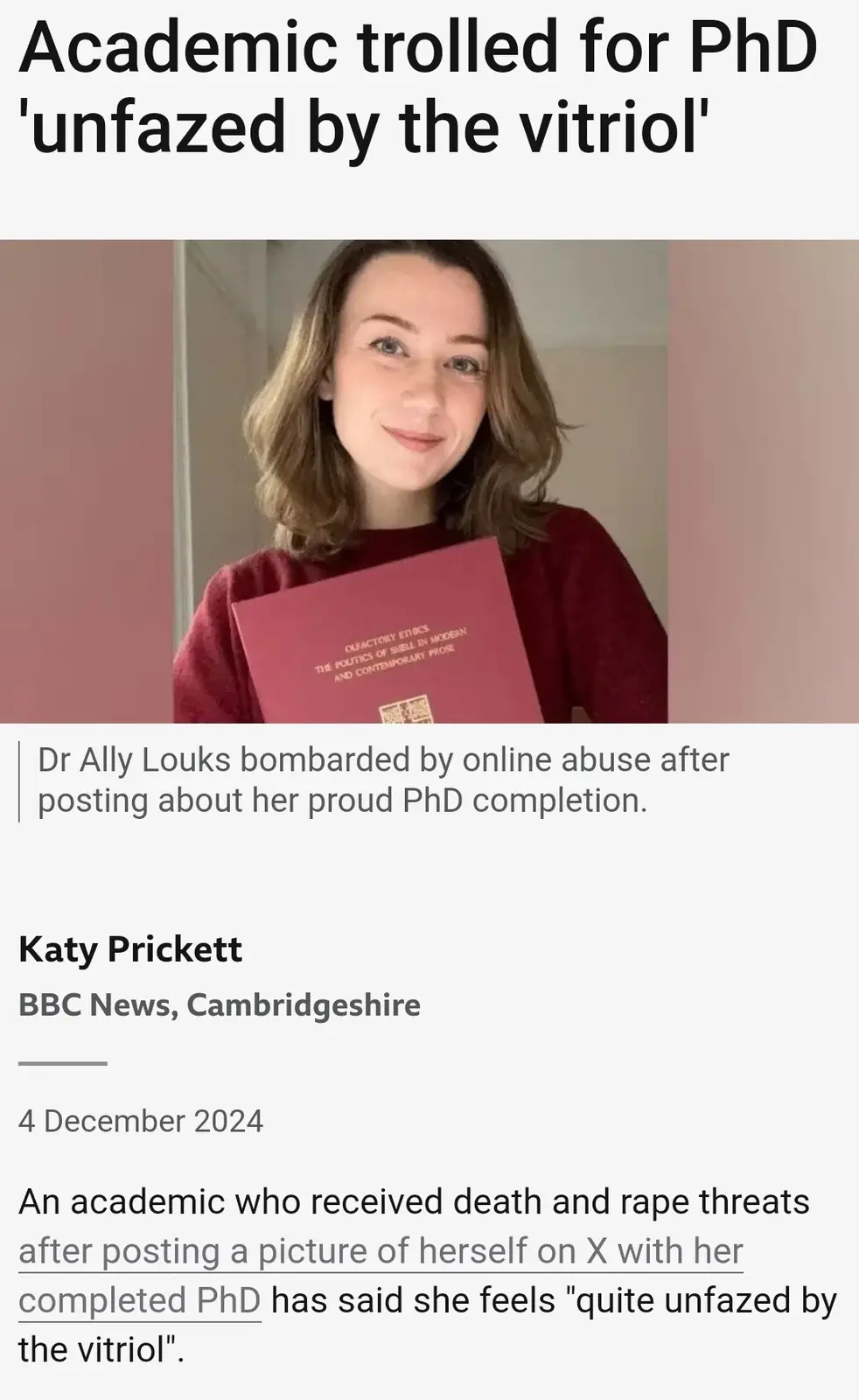 A woman with shoulder-length brown hair, wearing a red sweater, smiles while holding a red PhD certificate titled 'OLFACORY…