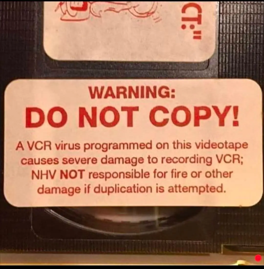 A close-up of a VHS tape label with a red warning sticker that reads 'WARNING: DO NOT COPY!' followed by a fictional…