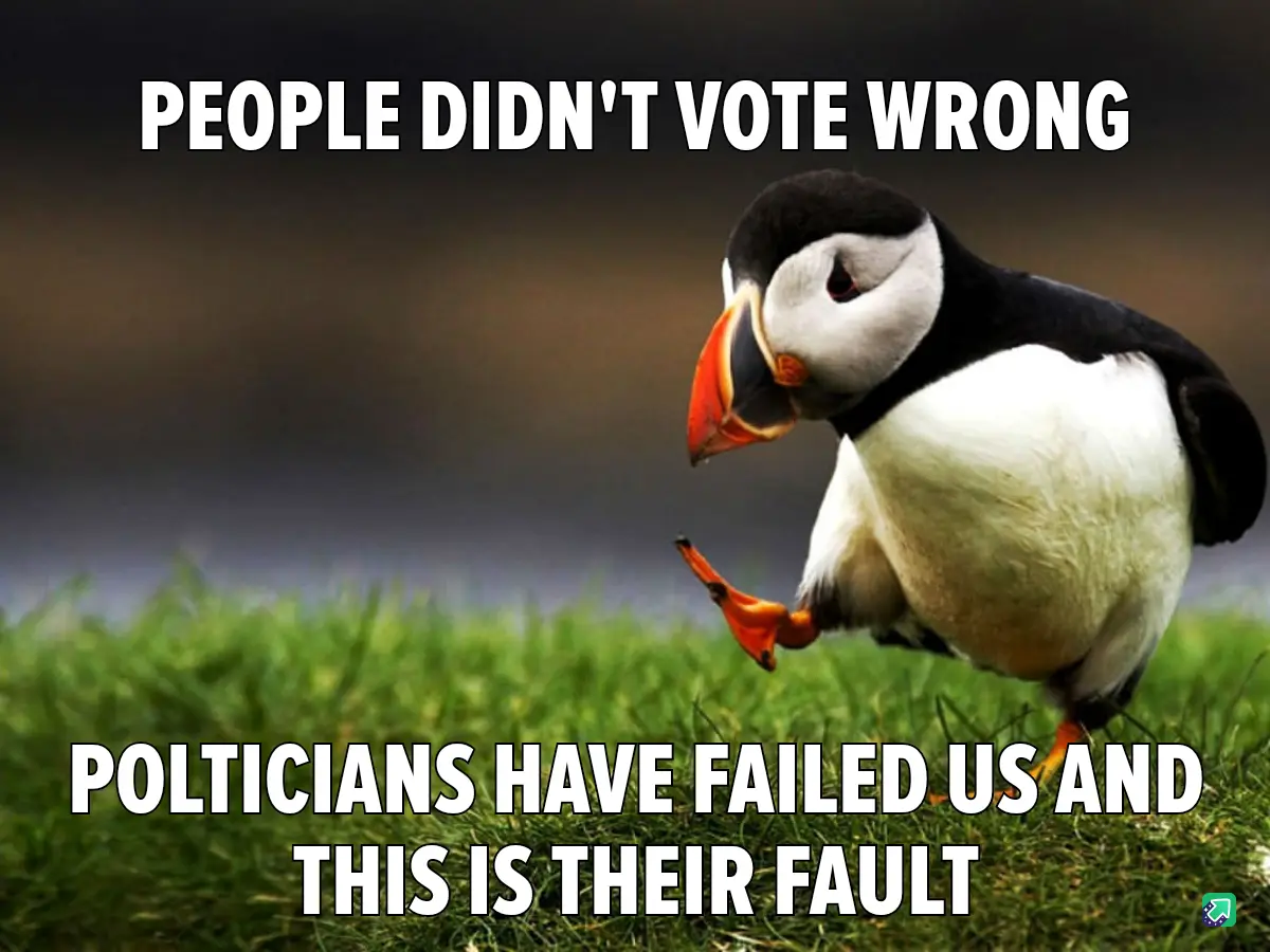 A photograph of a puffin standing on green grass with a blurred background, looking down with a slightly dejected or…