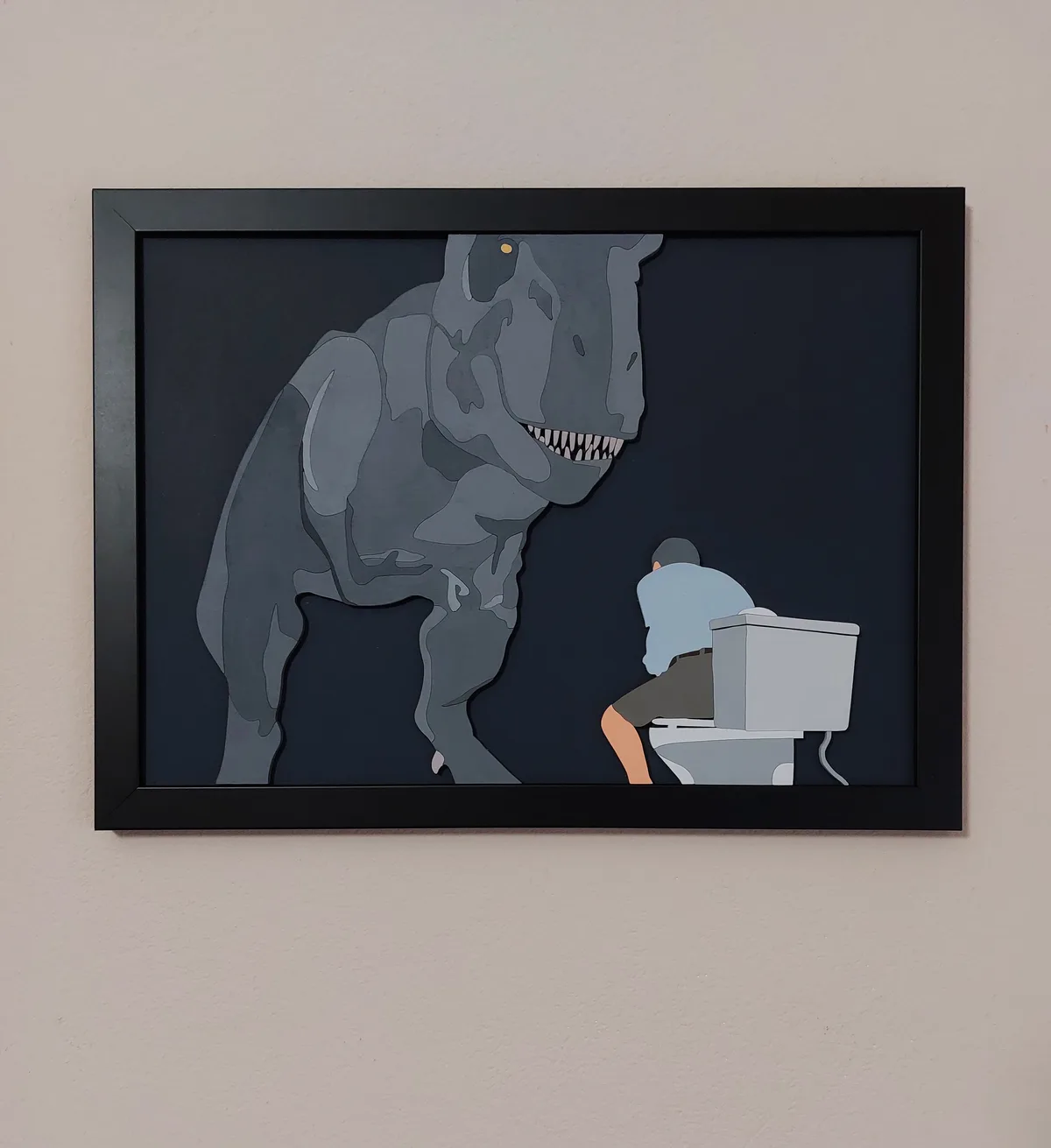 A framed artwork depicts a large, menacing grey T-Rex looming over a person sitting on a toilet. The person is shown from…