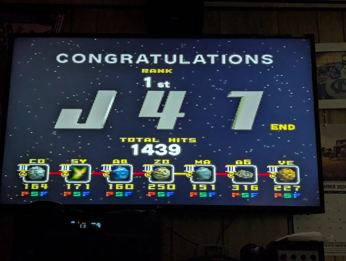A screenshot of a retro-style arcade game ending screen showing 'CONGRATULATIONS RANK 1st J47 END' with 'TOTAL HITS 1439'…
