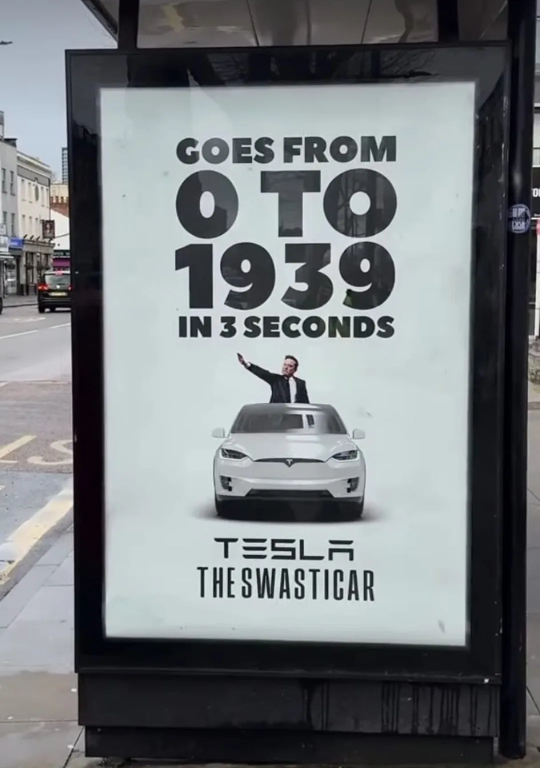 A bus stop advertisement features a white Tesla car with a man in a suit waving from the roof. The text claims the car 'goes…
