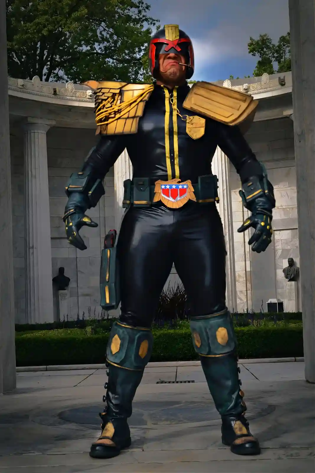 A person in a full-body costume resembling the comic book villain MODOK stands in front of a classical-style building with…