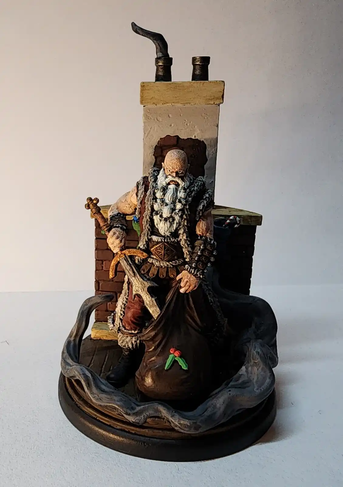 A figurine depicts a bearded, armored Santa Claus sitting on a throne that is a miniature brick fireplace with a chimney. He…