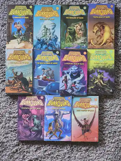 A collection of eleven paperback books from 'The Martian Tales of Edgar Rice Burroughs' series, arranged in three rows on a…