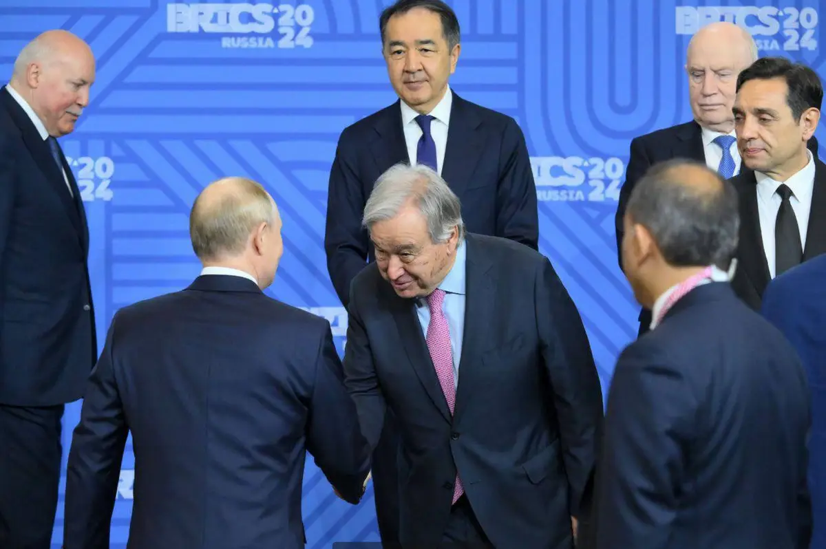 A photo from the BRICS 2024 summit in Russia shows UN Secretary-General António Guterres bowing slightly while shaking hands…