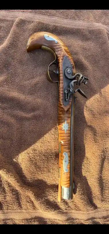 a flintlock pistol with a curved wooden grip, ornate metal fittings, and a star-shaped inlay, lies vertically on a textured…