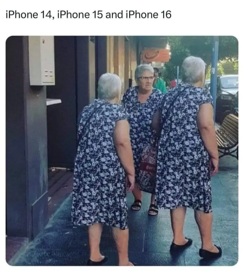 Three elderly women in matching blue and white floral dresses stand on a sidewalk, viewed from behind. The woman in the…