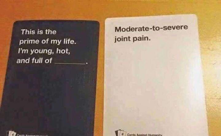 Two Cards Against Humanity cards are placed side by side on a wooden surface. The left card is dark blue with white text…