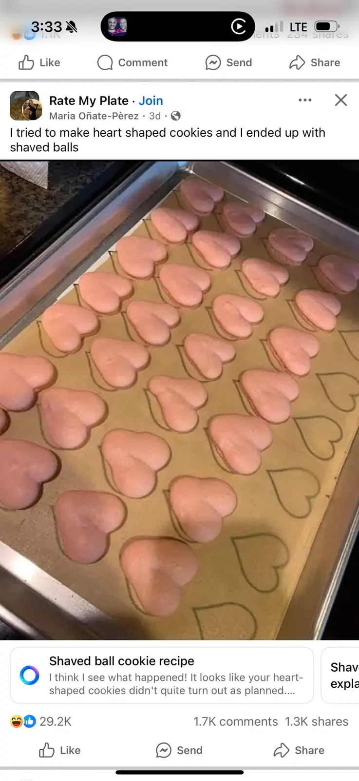 A baking tray holds numerous pink, heart-shaped cookies that are visibly misshapen, resembling flattened, shaved balls…