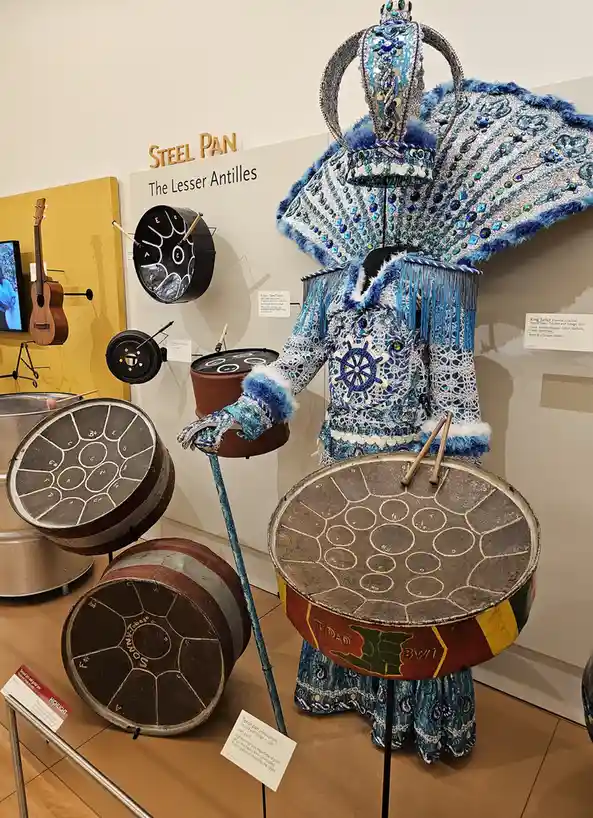 A museum exhibit displays a highly ornate blue and silver carnival costume labeled 'King Sailor' from Port of Spain…