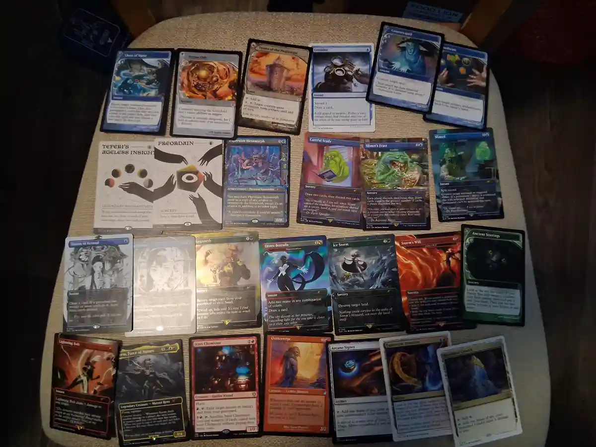 A collection of Magic: The Gathering cards is spread out on a beige tablecloth, featuring various cards like 'Chain of…