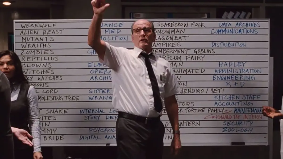 A man in a white shirt and black tie stands in front of a whiteboard filled with handwritten categories like 'WEREWOLF'…