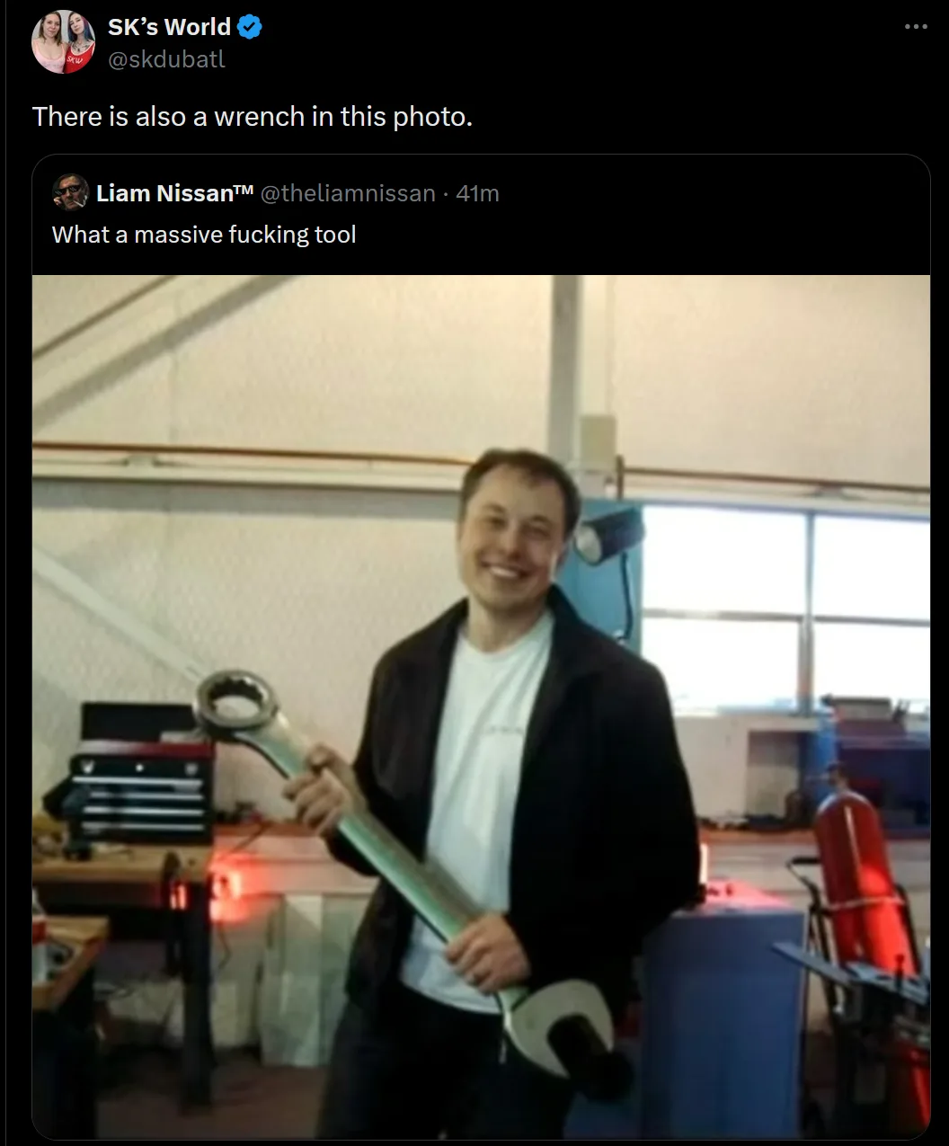 A man in a workshop holds an enormous, oversized wrench, smiling at the camera. The overlaid text reads 'What a massive…