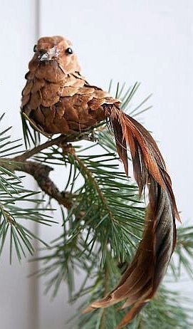 A pinecone is artfully arranged to resemble a bird perched on a pine branch, complete with a long, feathery tail made from…