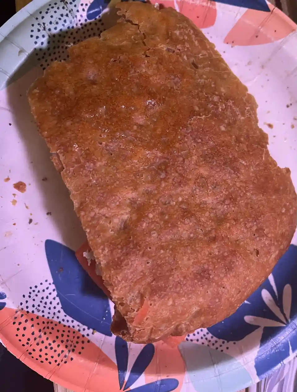 A close-up photo shows a large, golden-brown, crispy-looking food item, possibly a fried sandwich or a thick pancake…