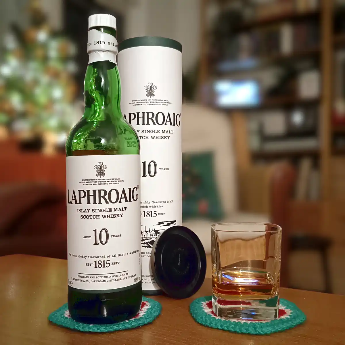 A green bottle of Laphroaig 10-year-old Islay single malt scotch whisky sits next to its white cylindrical box and a…