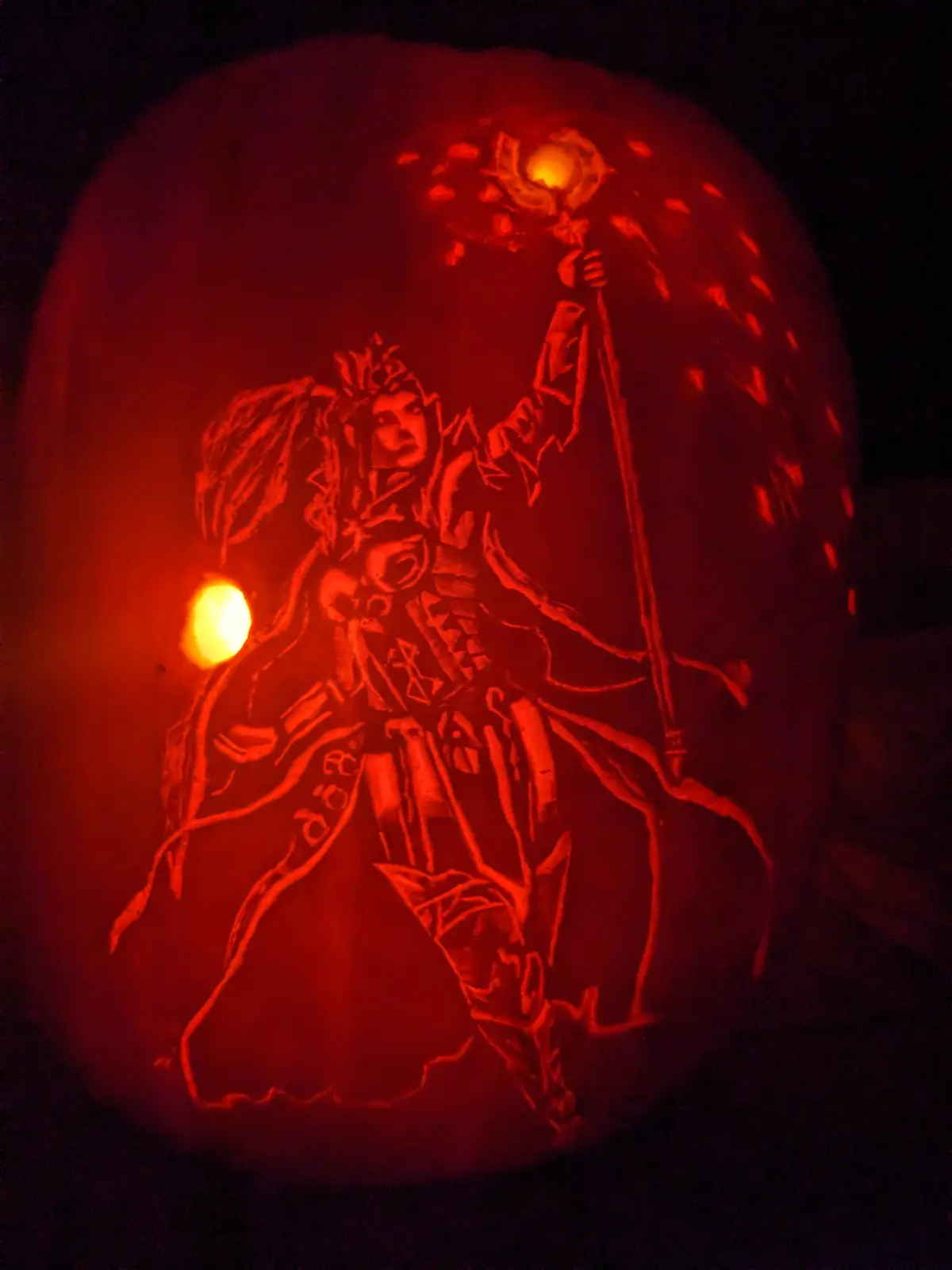 A carved pumpkin illuminated from within, depicting a detailed fantasy character holding a staff with a glowing orb, with a…
