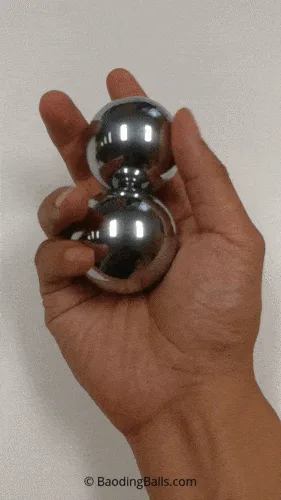 A grid of six images shows a hand manipulating two shiny, chrome-colored metal spheres, known as baoding balls, in various…