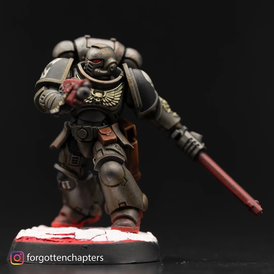 A painted miniature of a Space Marine from Warhammer 40,000, wearing dark grey power armor with red glowing eyes, holding a…