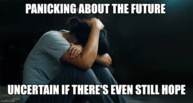 A person is shown sitting on the floor, hunched over with their head buried in their arms, conveying deep distress or…