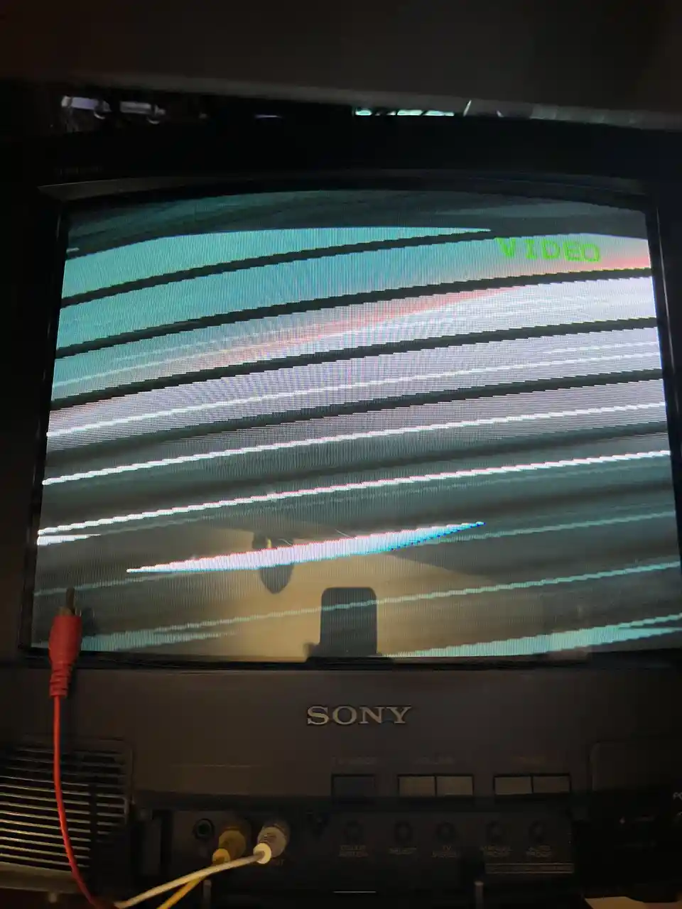 A close-up of a vintage Sony CRT television displaying severe horizontal video static and distortion, with the word 'VIDEO'…