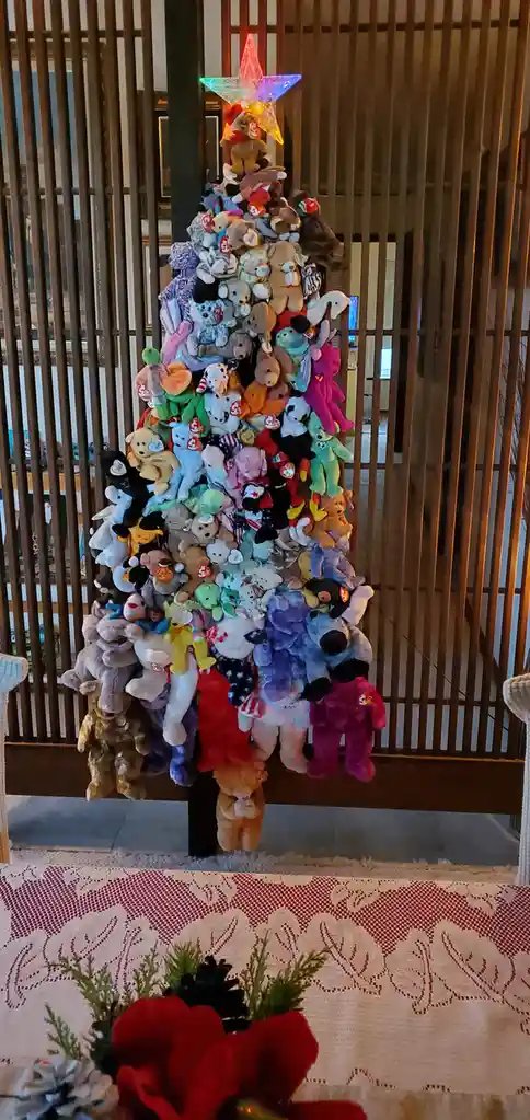 A Christmas tree made entirely of stuffed animals, mostly Ty Beanie Babies, piled in a triangular shape with a glowing star…