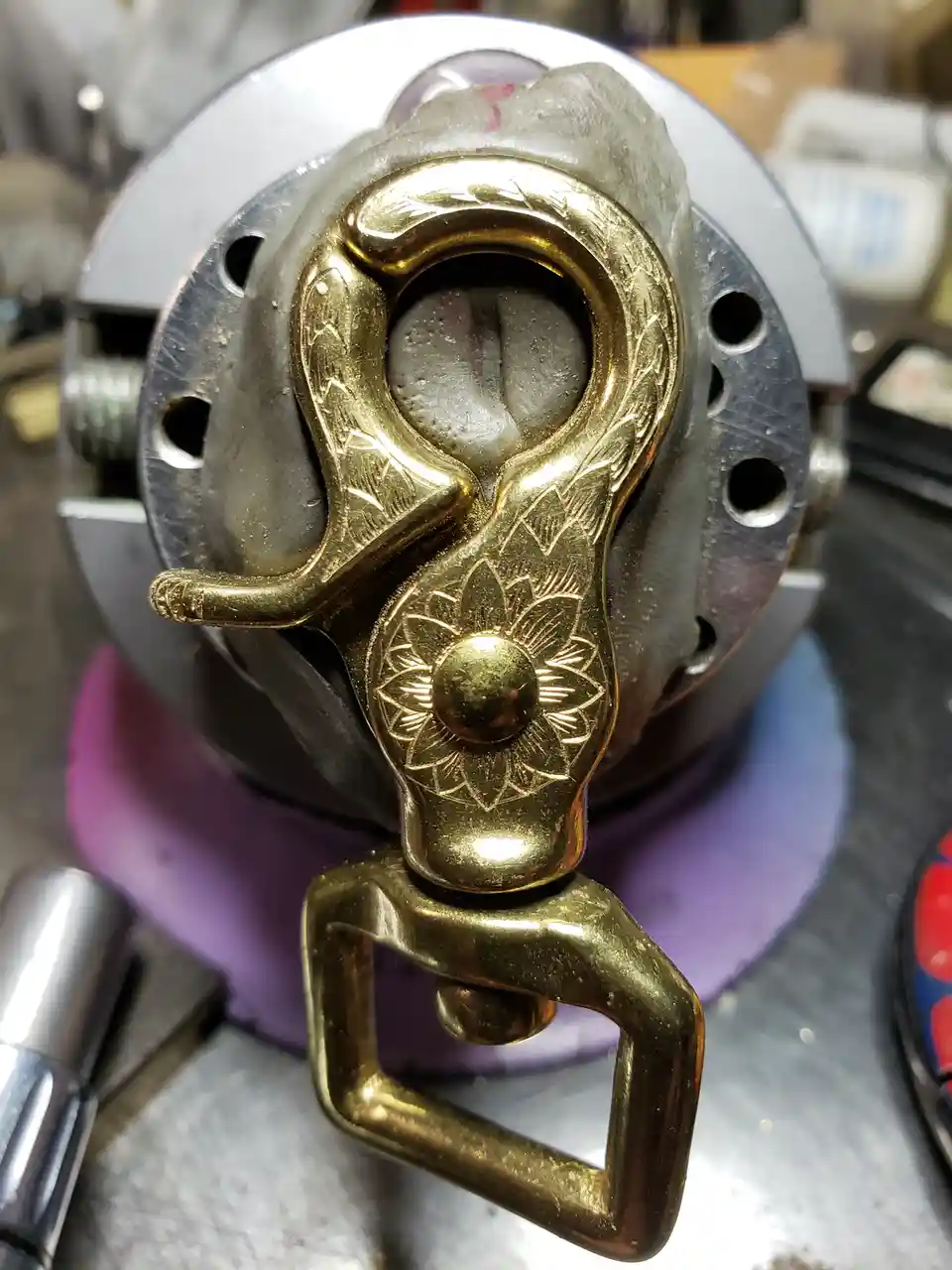 A close-up photo shows an ornate, brass-colored handle with floral engravings attached to a large, industrial metal object…