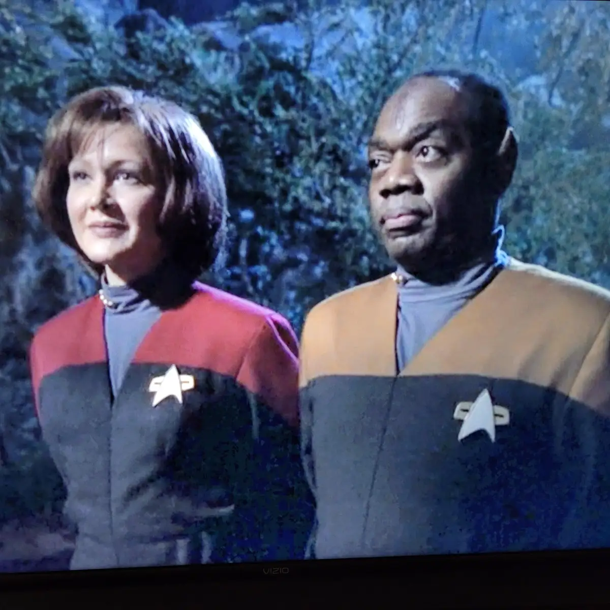 two star trek characters, one in a red uniform and one in a gold uniform, stand side by side with serious expressions. the…