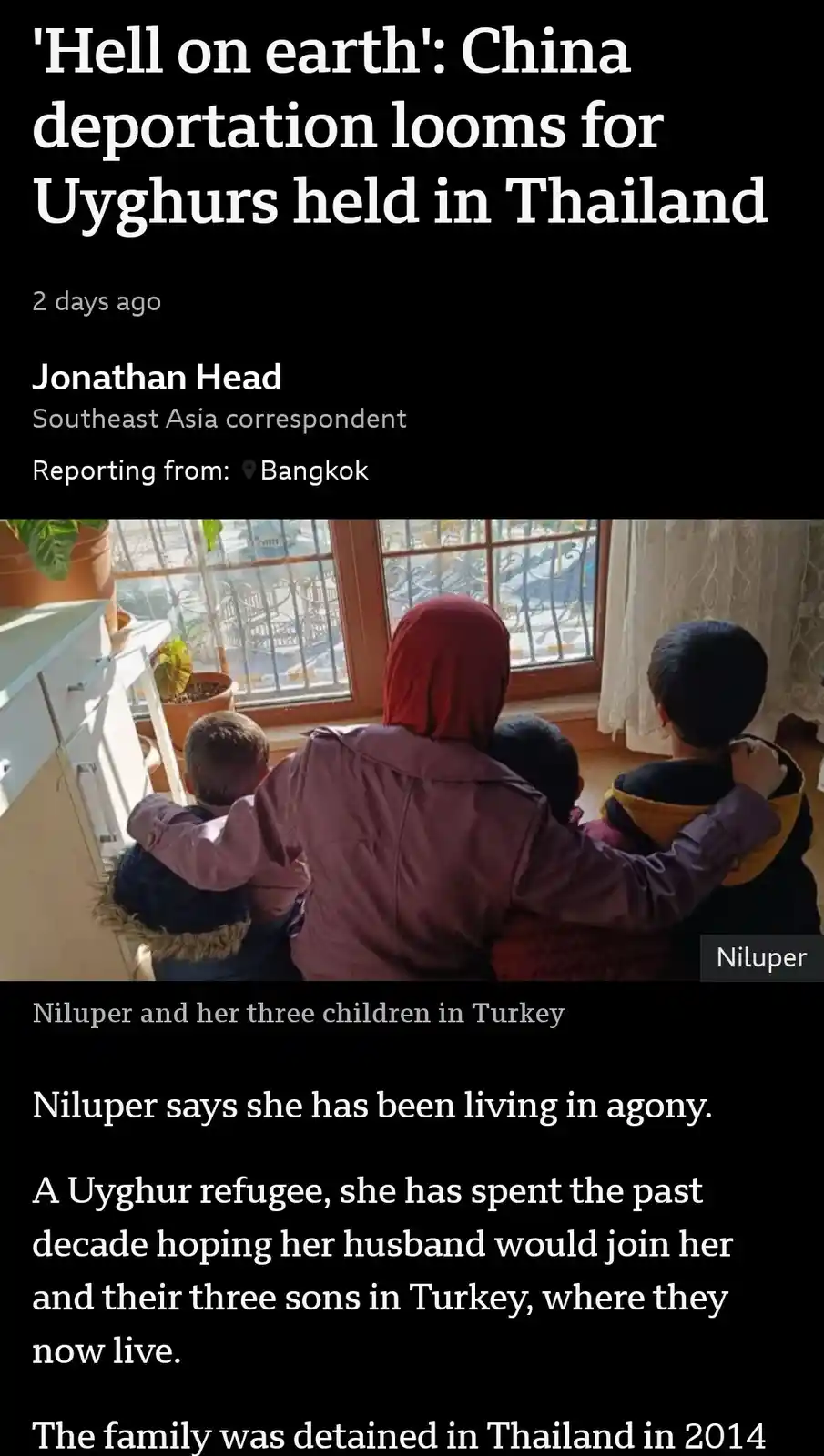A screenshot of a news article shows a photo of a woman in a red headscarf and purple jacket embracing three children from…