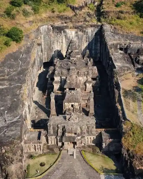 an aerial view of the ancient kailashnath temple carved directly into a mountain cliff face, with steep stairs leading up to…