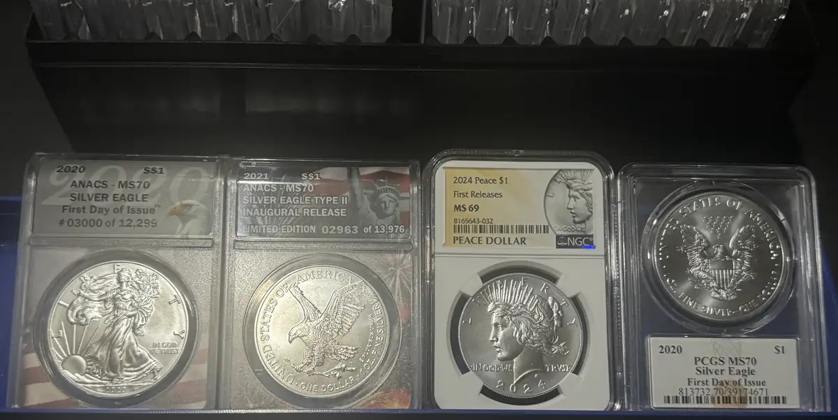 Four graded U.S. silver coins in protective slabs are displayed side-by-side on a shelf. From left to right: a 2020 ANACS…