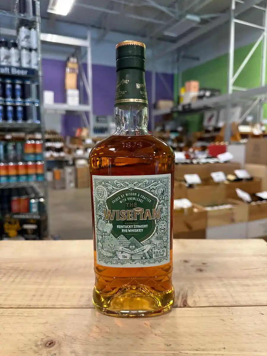 A bottle of 'The Wiseman' American Kentucky Straight Rye Whiskey sits on a wooden counter in what appears to be a liquor…